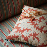 Cushion made from a printed linen fabric sample in orange, blue and off white featuring a stylized coral pattern.