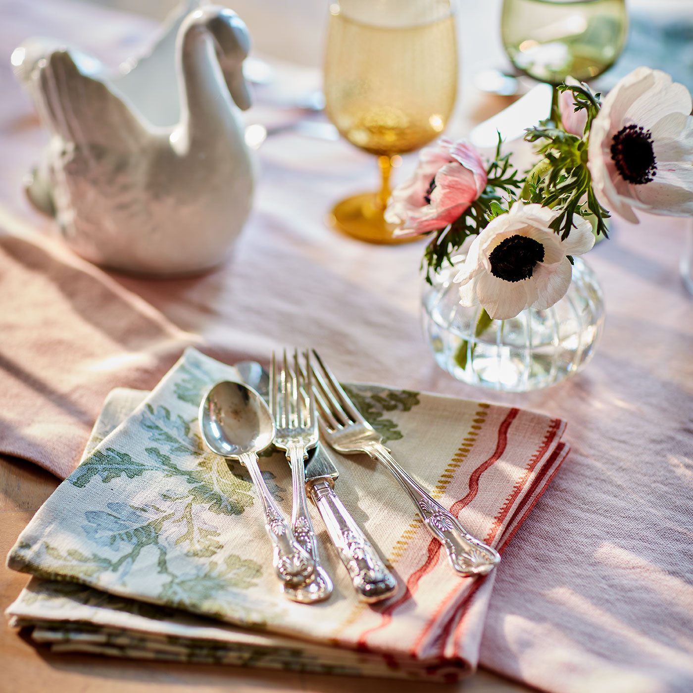 Napkins in a printed linen fabric with pink and green stripes and an oak-leaf motif.