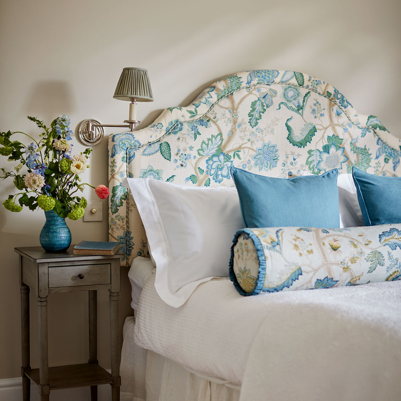Headboard in a printed linen fabric with tree of life design in blue and green colours.