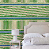 Bedroom with a playful green and blue wallpaper with a combination of tonal stripes, zigzags, and matching colour bands.