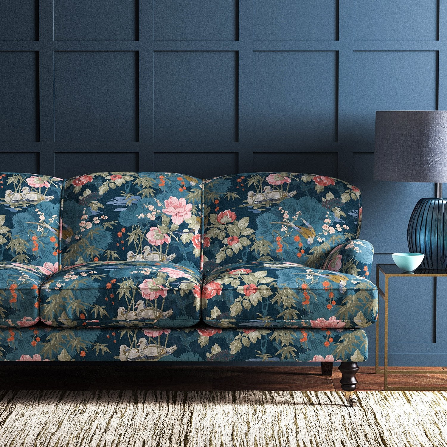 Sofa upholstered in a blue-coloured velvet upholstery fabric with a floral and bird design with a stain resistant finish.