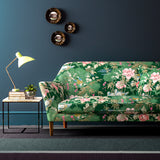 Sofa upholstered in an emerald coloured velvet upholstery fabric with a floral and bird design with a stain resistant finish.