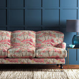 Sofa covered in a printed velvet upholstery fabric showcasing a pink Japanese tree design.