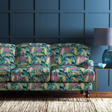 Sofa covered in a floral-style printed velvet fabric in pink, green and blue.