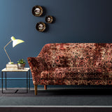 Sofa covered in a velvet upholstery fabric with  an antique carpet-style design.