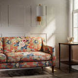 Sofa covered in a printed linen fabric with bouquets of roses on an orange backdrop.