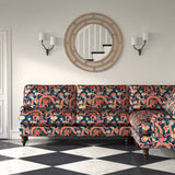 Velvet sofa upholstered in a printed velvet fabric with a intricate mirror dragon design in blue and orange colours.
