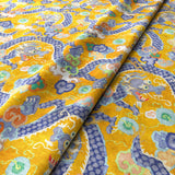 Printed velvet fabric with intricate mirror dragon design in yellow colours, for upholstery and curtain use.