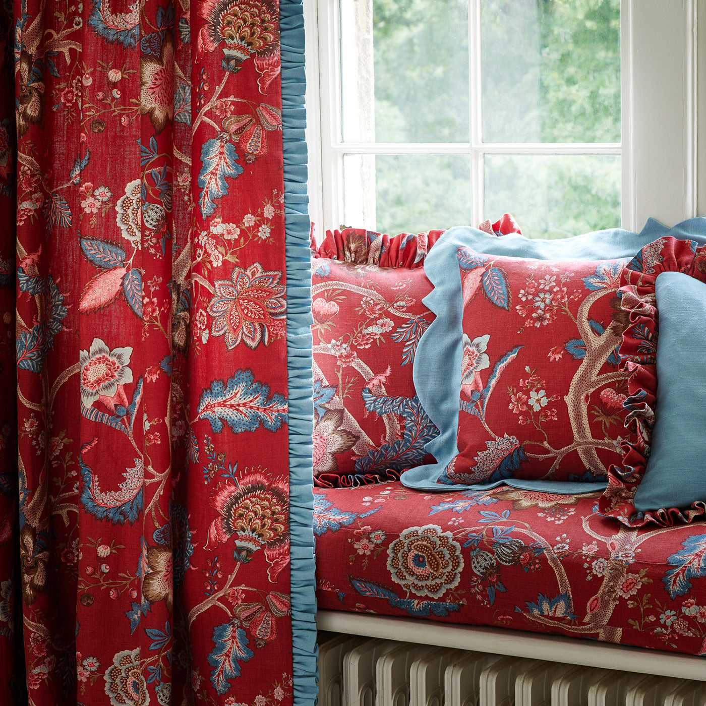 Curtains and cushions in a printed linen fabric with tree of life design in red and blue colours.