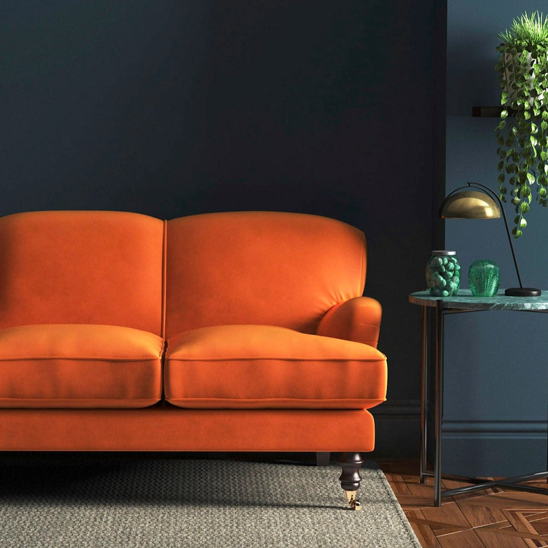 Sofa covered in a orange velvet upholstery fabric