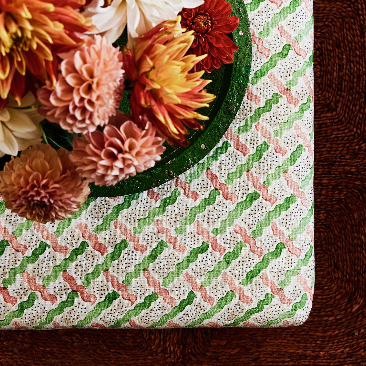 Printed linen fabric - a contemporary lattice design in green, pink, cream and white – on a footstool.