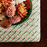 Printed linen fabric - a contemporary lattice design in green, pink, cream and white – on a footstool.