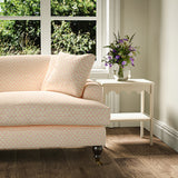 Printed linen fabric – a classic trellis design in pink, yellow, and cream – on a sofa
