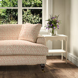 Printed linen fabric – a hand drawn; mirrored leaf motif pattern in red and cream – on a sofa