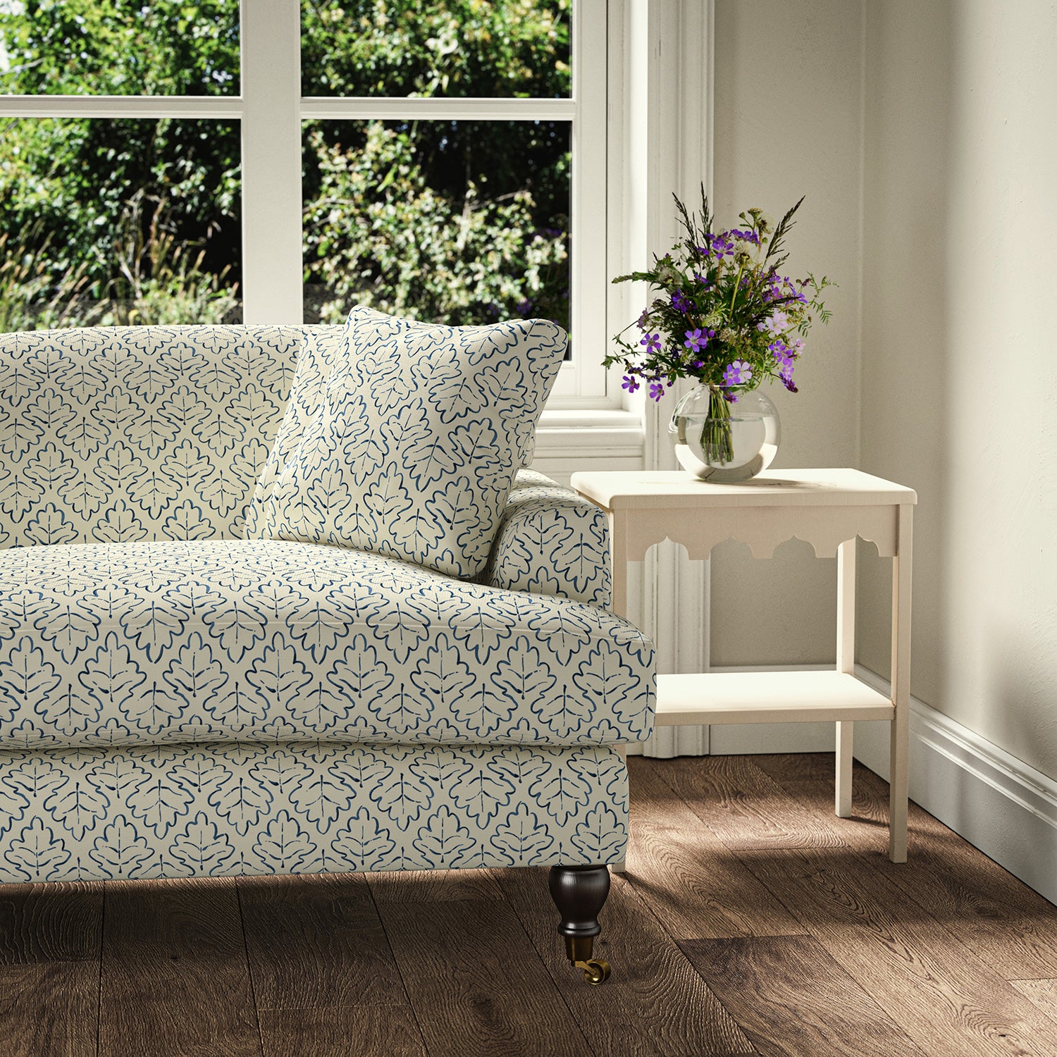 Printed linen fabric – a hand drawn; mirrored leaf motif pattern in blue and cream – on a sofa