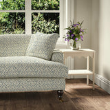 Printed linen fabric – a hand drawn; mirrored leaf motif pattern in blue and cream – on a sofa