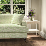 Printed linen fabric – a hand drawn; mirrored leaf motif pattern in green and cream – on a sofa