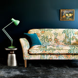 Sofa covered in a printed velvet fabric showing a tropical leaf design in pink