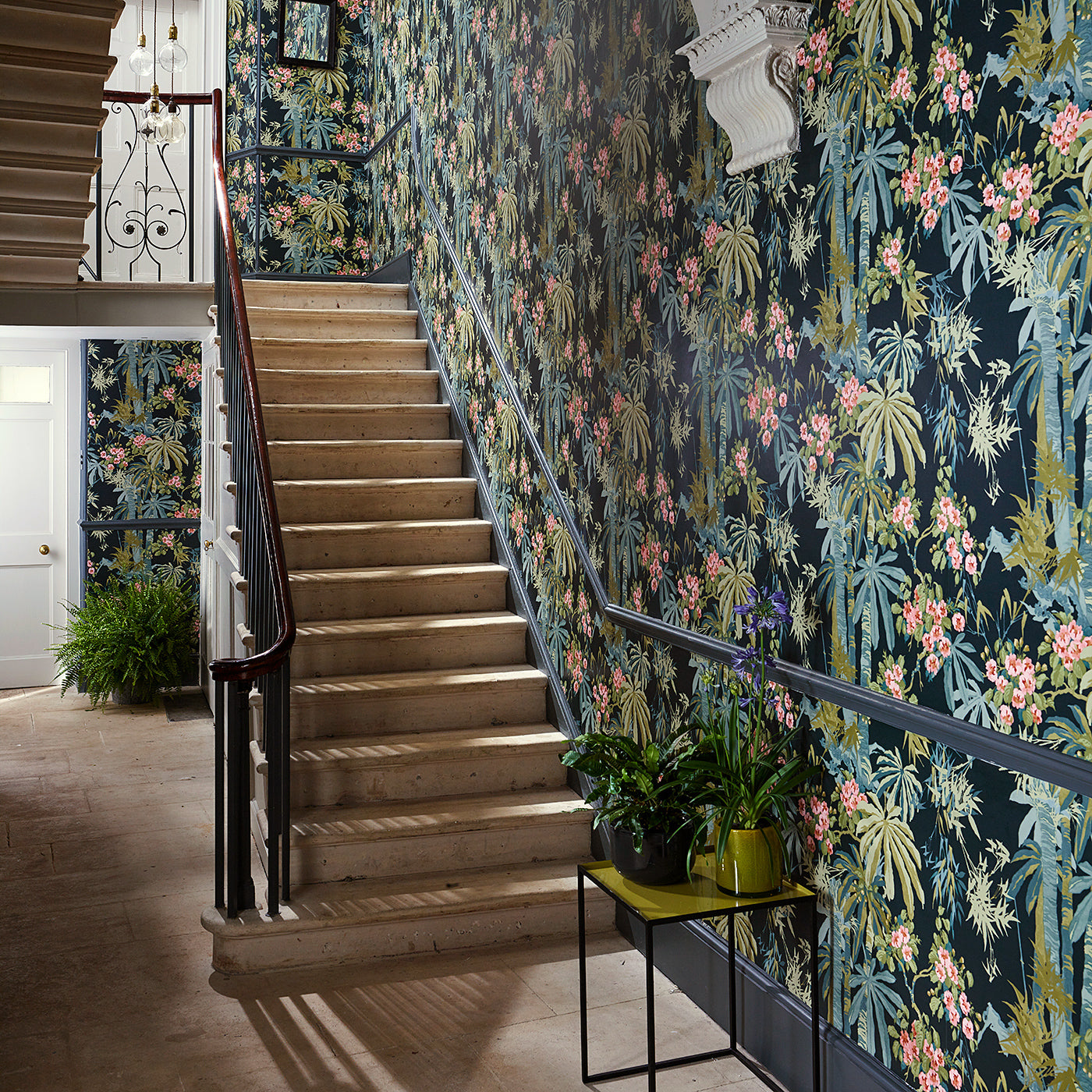 Hallway with a tropical wallpaper in navy with exotic, floral blossoms intertwined with bamboo.