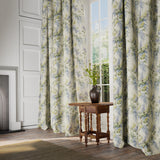 Curtains in a printed linen fabric with a wisteria floral pattern in yellow, green and blue colours.