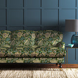 A printed velvet fabric showcasing an archival document, circa 1700s, this stylised floral is lavish, graceful, and timeless in green on a sofa
