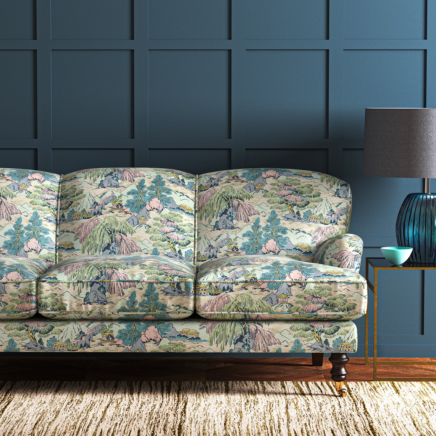 A printed velvet fabric showcasing a beautiful landscape of mountains, willows, and Oriental-style buildings in blue, pink and green on a sofa