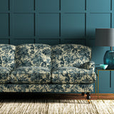 A printed velvet fabric showcasing a landscape of palms and monkeys in blue and cream on a sofa