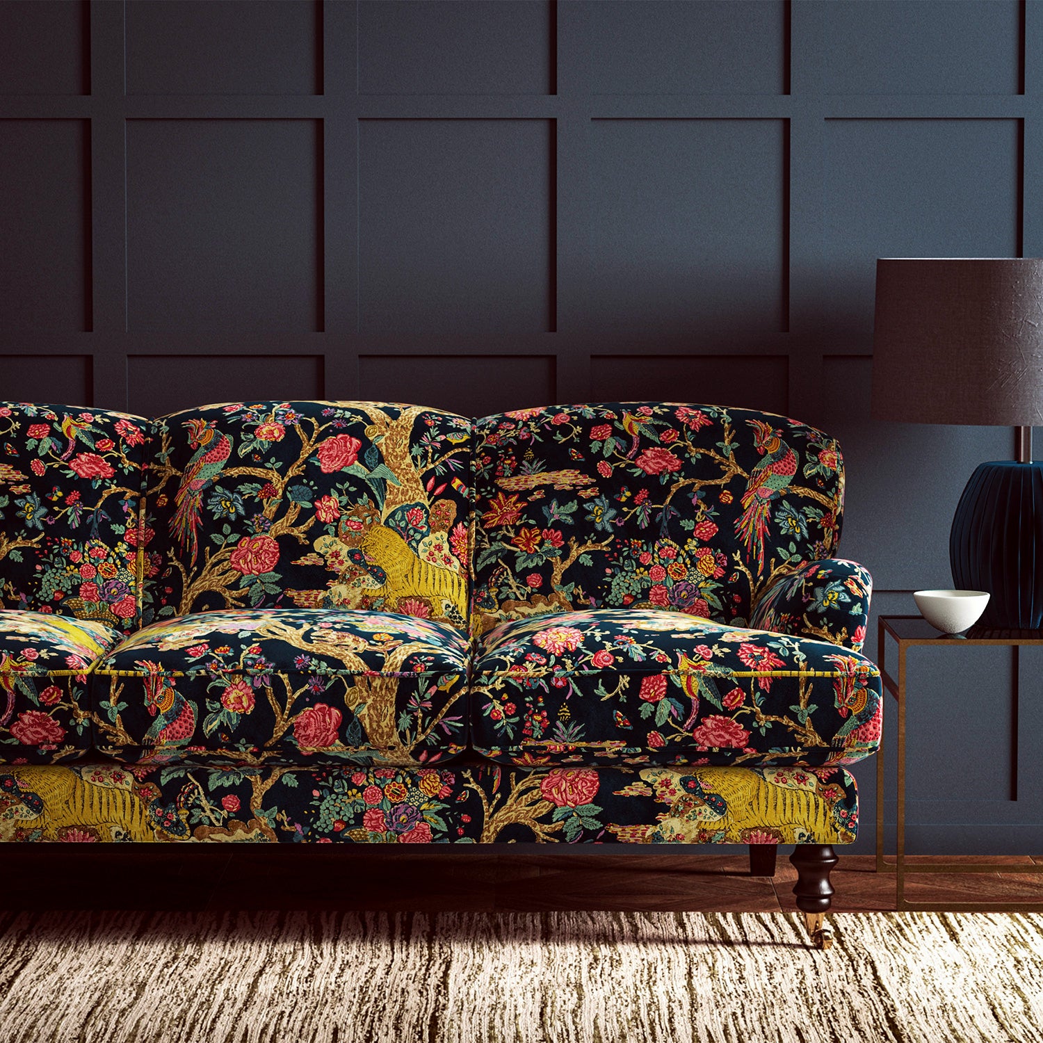 A printed velvet fabric depicts a menagerie of parrots, lions, and alluring flowers in blue on an sofa