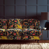 A printed velvet fabric depicts a menagerie of parrots, lions, and alluring flowers in blue on an sofa